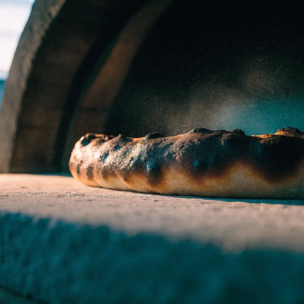 Vastag pizzatészta pereme a köves kemence alján, elszenesedett hólyagokkal